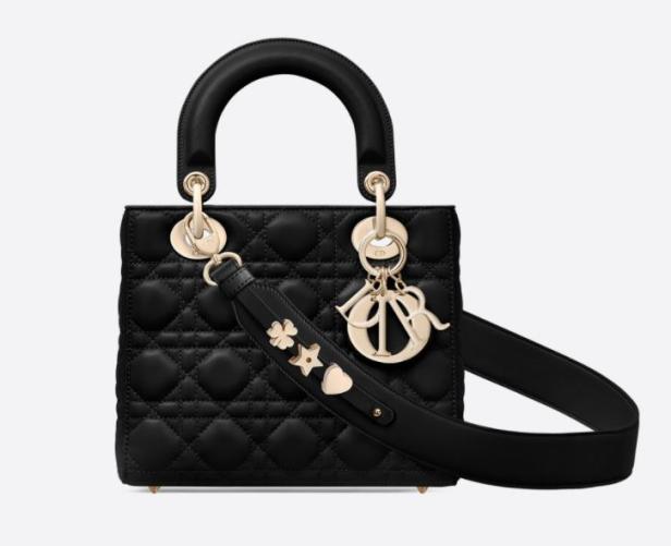 Eine schwarze „Lady Dior“ Handtasche mit goldenen Anhängern und einem Schulterriemen.