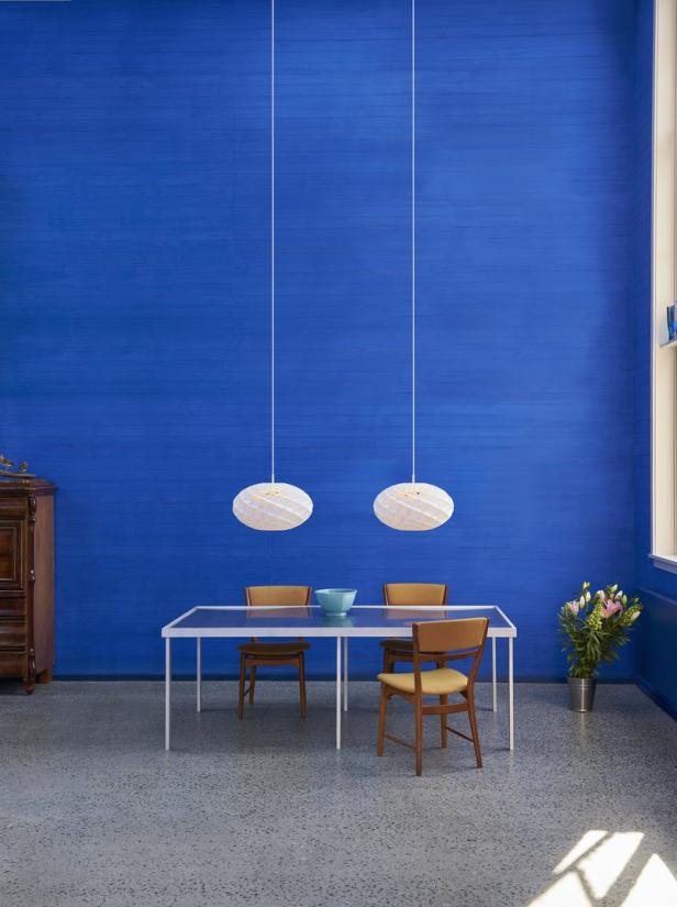 Ein Esszimmer mit blau gestrichenen Wänden, einem Tisch und zwei Hängelampen.