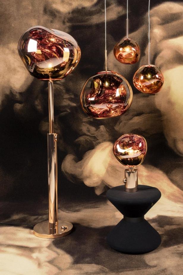 Mehrere moderne Lampen mit rosafarbenen Glasschirmen vor einem gemusterten Hintergrund.