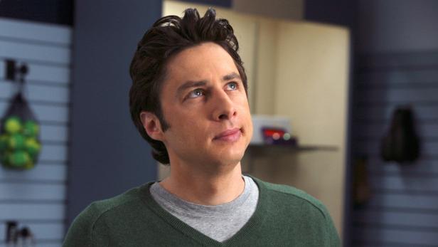 Zach Braff schaut in einem grünen Pullover nach oben.