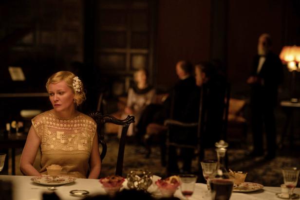 Kirsten Dunst sitzt bei einer Dinnerparty nachdenklich am Tisch.