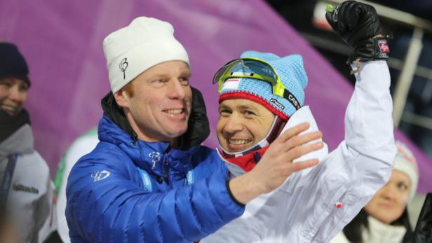 Zwei Männer umarmen sich und lächeln, einer mit einer Skibrille auf der Stirn und einer dänischen Flagge auf dem Handschuh.