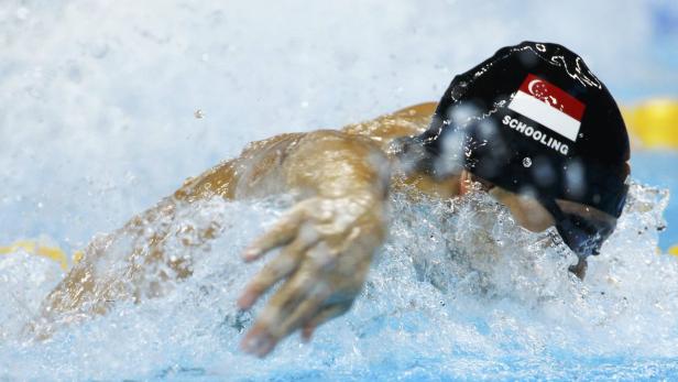 Ein Schwimmer mit einer Badekappe mit der Flagge von Singapur schwimmt im Wasser.