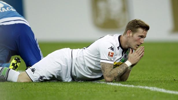 Ein Fußballspieler liegt auf dem Rasen und hält die Hände vors Gesicht.