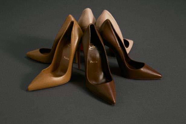 Mehrere High Heels der Marke Christian Louboutin in verschiedenen Brauntönen stehen auf grauem Grund.