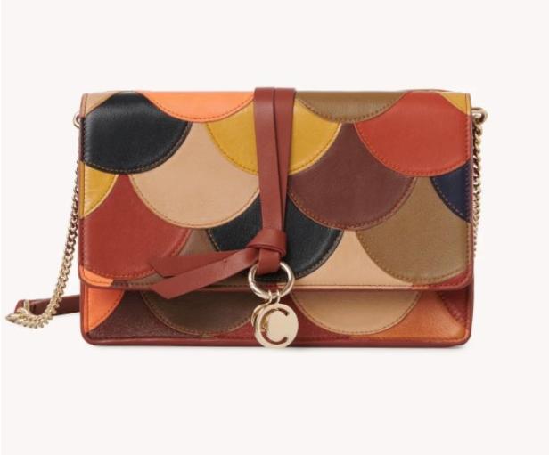 Eine bunte Handtasche mit einem Muster aus Lederkreisen und einem goldenen Kettenriemen.