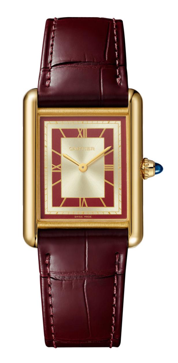 Eine goldene Cartier Tank Armbanduhr mit einem burgunderroten Lederarmband.