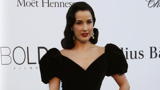 Dita Von Teese in einem schwarzen Kleid mit Puffärmeln und roten Lippen.