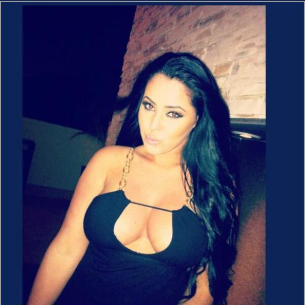 Eine Frau mit dunklen, langen Haaren und einem schwarzen Kleid posiert für ein Foto.
