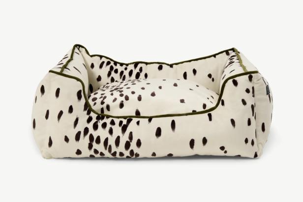 Ein Hundebett mit Dalmatiner-Muster und grünem Rand auf einem weißen Hintergrund.