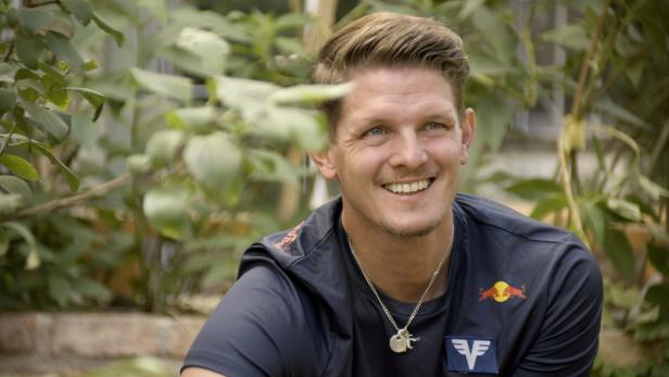 Thomas Morgenstern lächelt vor einem Hintergrund aus Pflanzen.