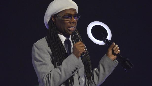 Nile Rodgers hält eine Auszeichnung mit einem ringförmigen Licht in der Hand.