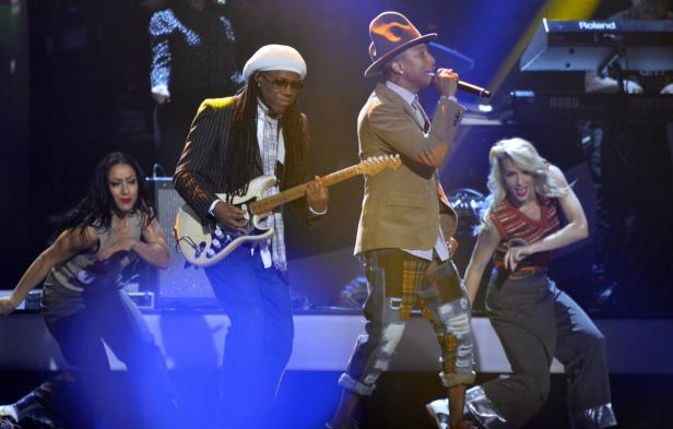 Pharrell Williams singt mit Gitarrist Nile Rodgers und Tänzerinnen auf einer Bühne.