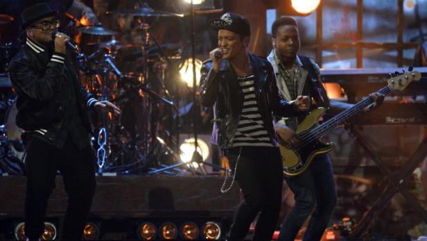 Bruno Mars tritt mit seiner Band auf einer Bühne auf.