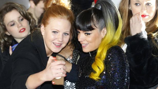 Lily Allen posiert mit einem Fan für ein Foto.