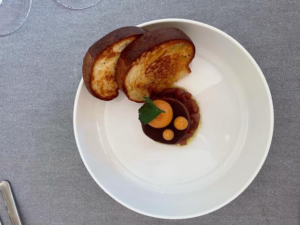 Ein Teller mit Tatar, pochiertem Eigelb und geröstetem Brot.