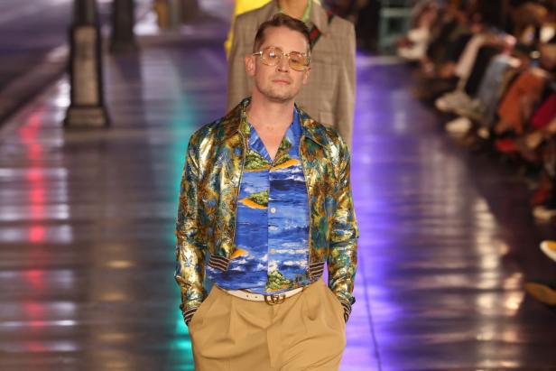 Macaulay Culkin läuft auf einer Modenschau in einem blau-goldenen Outfit.