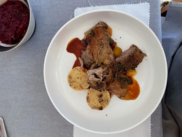 Ein Teller mit Fleisch, Knödeln und Rotkohl wird serviert.