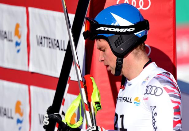 Ein Skirennläufer mit Helm und Skiern steht vor einer Vattenfall-Werbung.