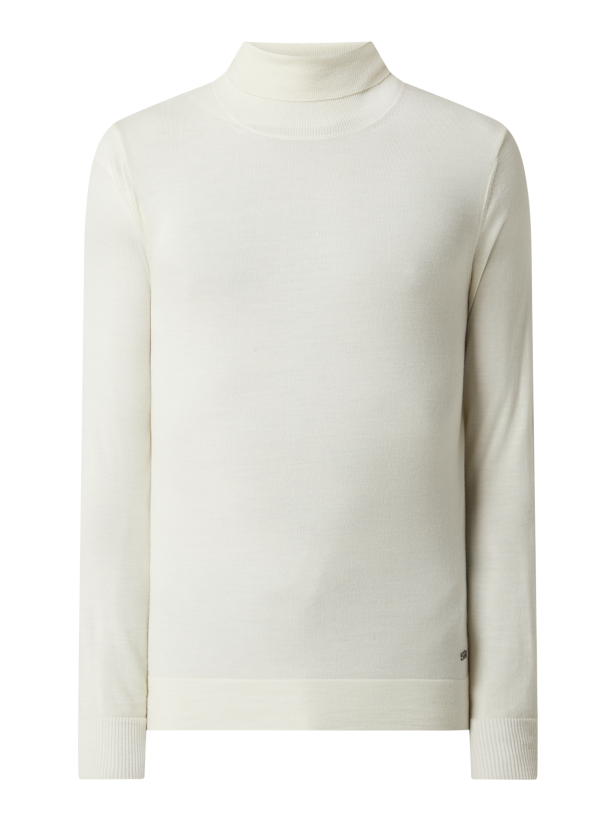 Ein cremefarbener Rollkragenpullover vor einem schwarzen Hintergrund.