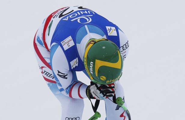 Ein Skirennläufer beugt sich mit gesenktem Kopf nach vorne.