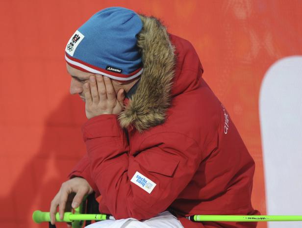 Ein Mann in roter Jacke und blauer Mütze sitzt nachdenklich da.