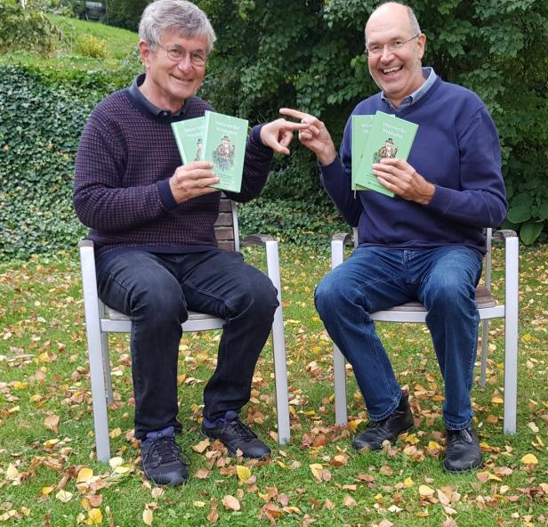 Zwei Männer sitzen im Garten und präsentieren das Buch „Weinviertler Weisheiten“.