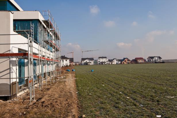 Reihenhäuser im Bau mit Gerüst an der Fassade am Dorfrand