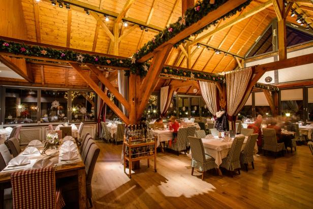 Ein festlich geschmücktes Restaurant mit Holzbalkendecke und gedeckten Tischen.