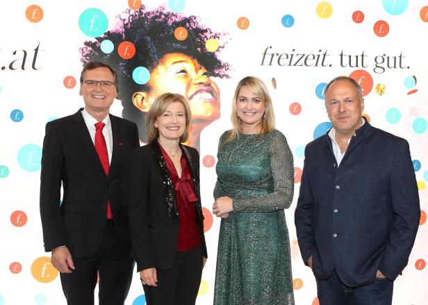 Vier Personen posieren vor einem Hintergrund mit dem Slogan „freizeit. tut gut.“.
