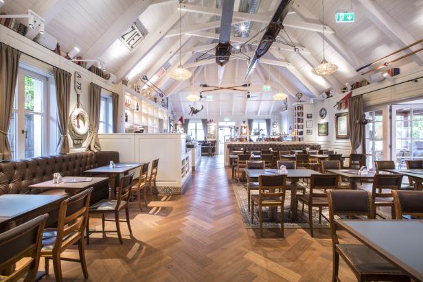 Innenansicht eines Restaurants mit nautischem Dekor und Holzboden.