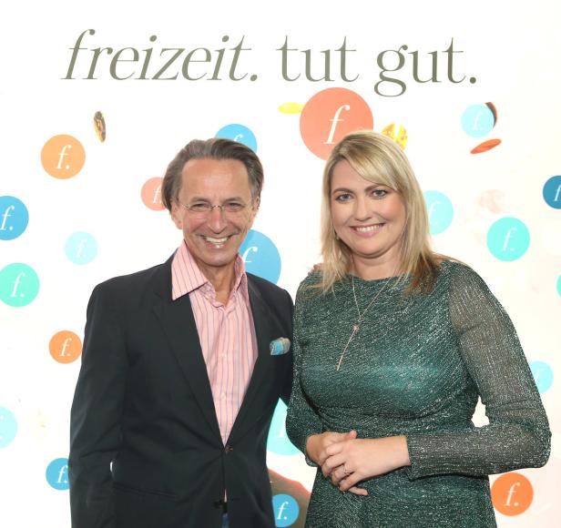 Ein Mann und eine Frau posieren vor einem Hintergrund mit der Aufschrift „freizeit. tut gut.“.
