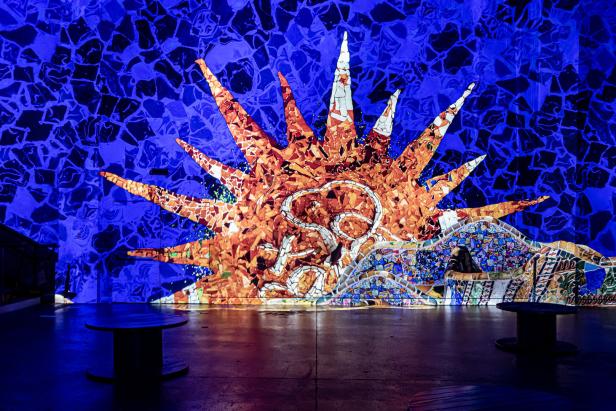 Eine Wand mit einem Mosaik, das eine Sonne und andere Motive darstellt.