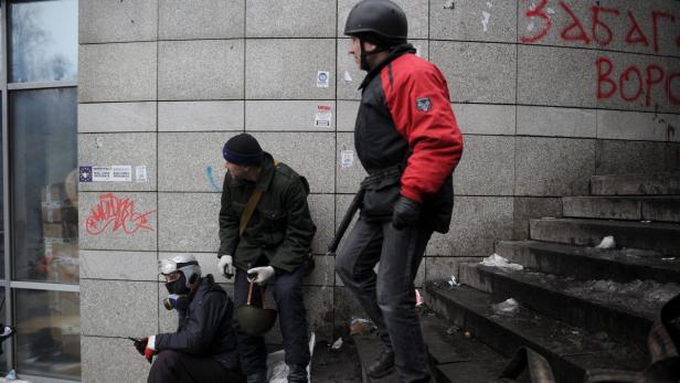 Drei Personen in Schutzkleidung stehen vor einer Wand mit Graffiti.