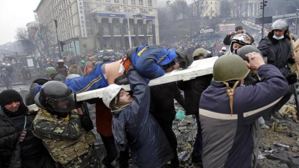 Sanitäter tragen einen verletzten Demonstranten während einer Demonstration in der Ukraine.