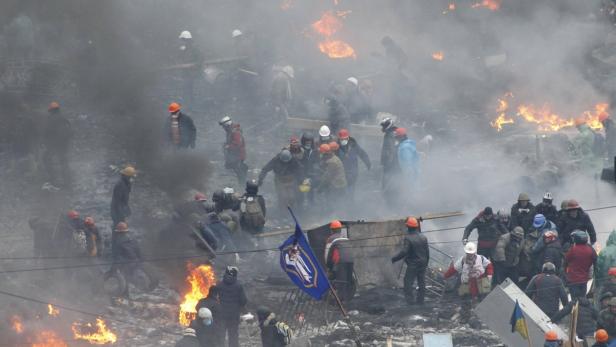 In Kiew stehen Demonstranten inmitten von Rauch und Feuer.