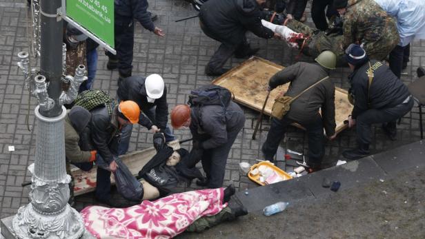 Helfer transportieren Verletzte und Tote während einer Demonstration.