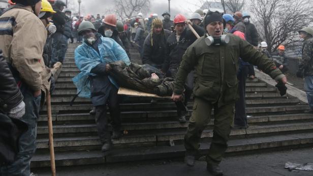Demonstranten tragen eine verletzte Person auf einer improvisierten Trage Treppen hinunter.