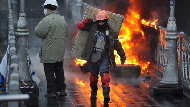 Ein Demonstrant mit Schutzschild geht an einem brennenden Barrikade vorbei.