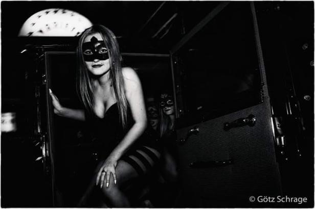 Eine Frau mit Maske steigt aus einem Oldtimer.