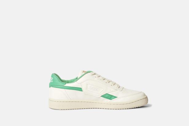 Ein weißer Sneaker mit grünen Akzenten der Marke SAYE.
