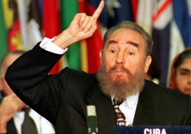 Fidel Castro gestikuliert vor einer Flaggenwand bei einer Rede für Kuba.