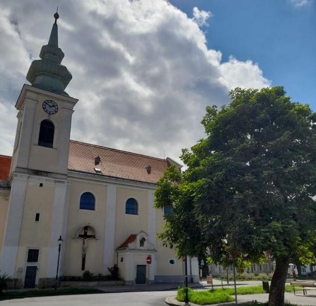 Eine Kirche mit einem Turm und einer Uhr unter einem bewölkten Himmel.