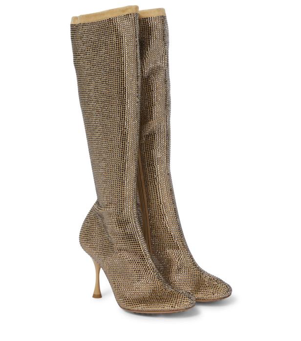 Ein Paar goldene, kniehohe Stiefel mit Absatz, die mit Strasssteinen besetzt sind.
