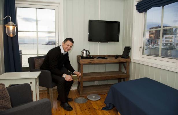 Ein Mann sitzt in einem Zimmer mit Meerblick und hält eine Angel in der Hand.
