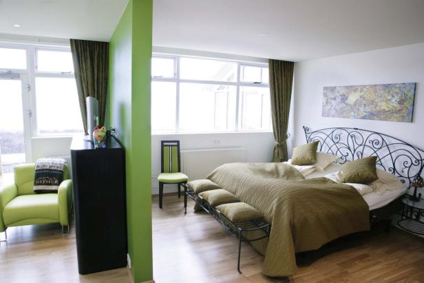 Ein Schlafzimmer mit einem Bett, einem Sessel und grünen Akzenten.