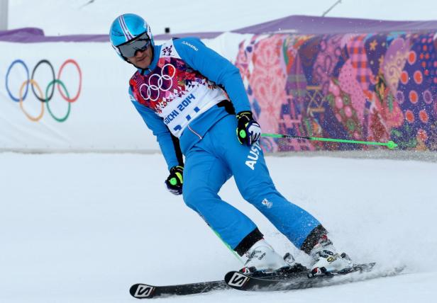 Ein Skirennläufer in blauer Kleidung fährt einen Hang hinunter.