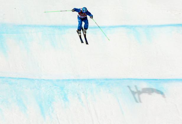 Ein Skifahrer springt in der Luft über eine schneebedeckte Piste.