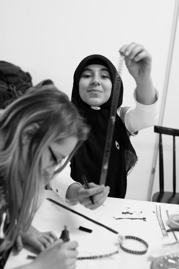 Eine junge Frau mit Hijab hantiert mit einem Filmstreifen.