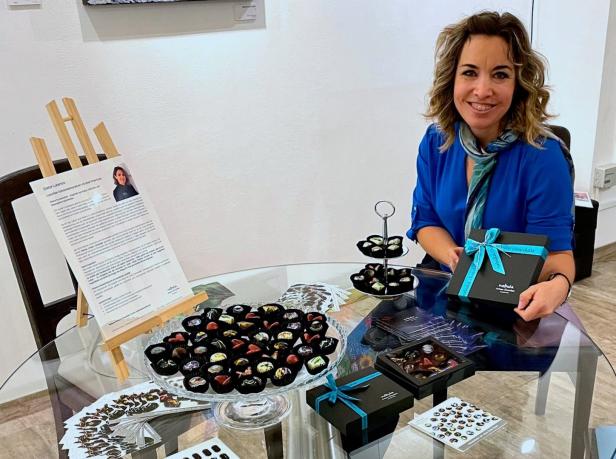 Eine Frau präsentiert Pralinen der Marke „Nebula Chocolate“ auf einem Tisch.